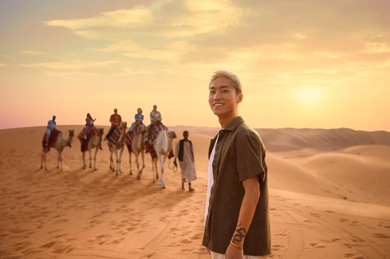 A camel caravan crossing the golden desert landscape of AlUla at sunset, retracing ancient Incense Road trade routes