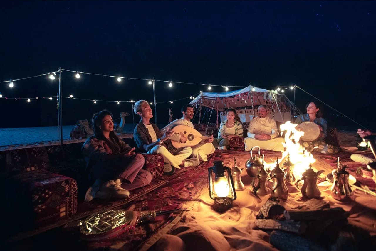 A candlelit dinner setup in the AlUla desert beneath the stars, with sandstone formations in the background