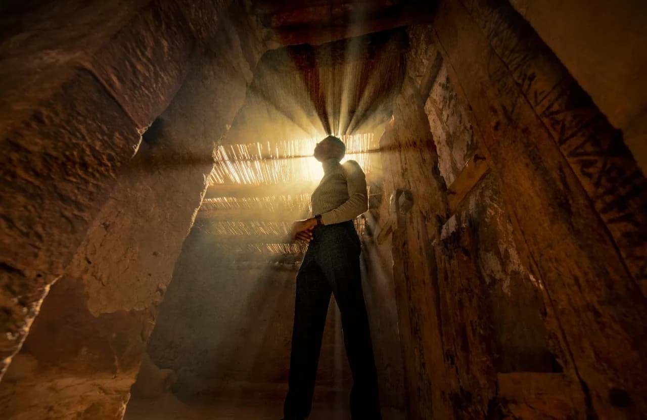 Sunbeams streaming through an ancient doorway in AlUla Old Town, illuminating centuries-old mud-brick walls