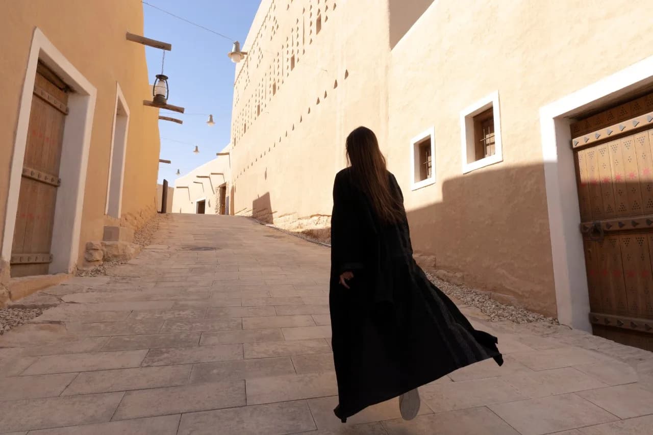 A visitor walking through the beautifully restored mud-brick pathways of At-Turaif district, Diriyah, Saudi Arabia